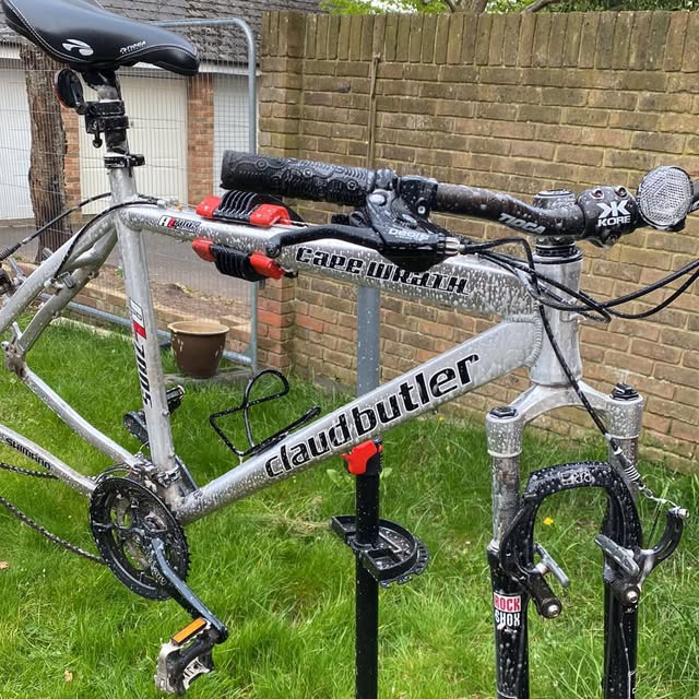 Blue hybrid commuter bike, serviced and cleaned, parked against a fence